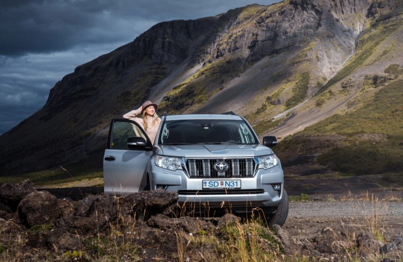 Toyota Land Cruiser 4x4 SUV parked below a dramatic mountain slope in Iceland